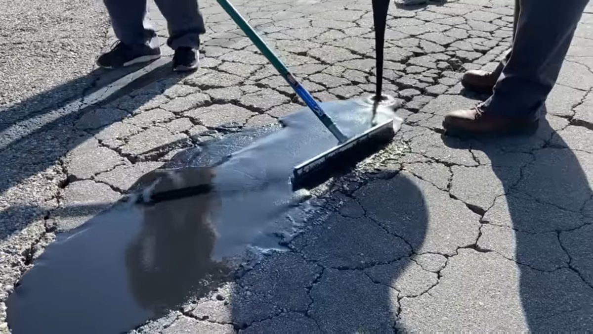 Spreading FastPatch ACR with squeegee over alligator cracks